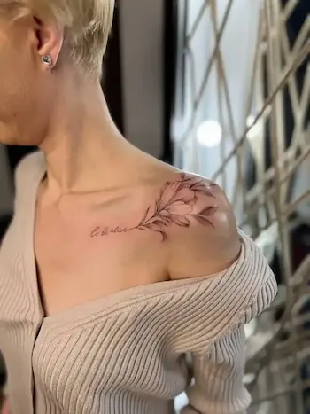 Татуировка на плече с надписью to be alive и веткой с листьями